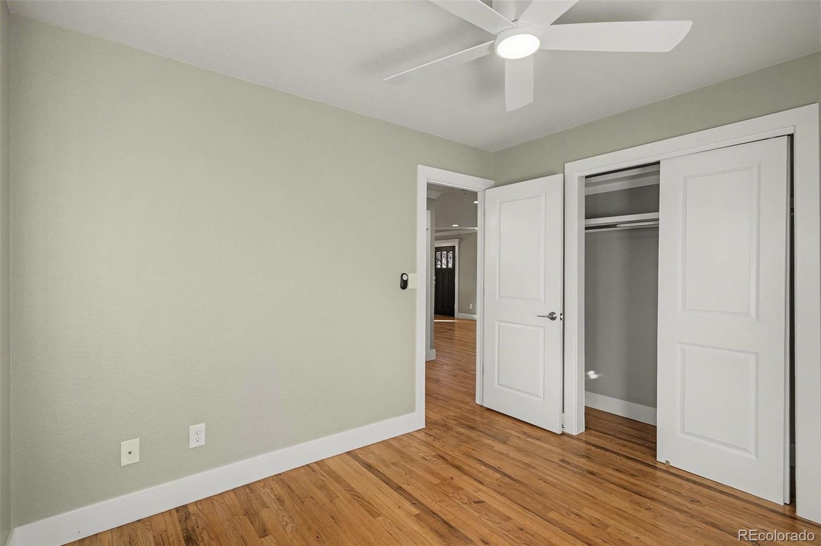 2580 South Perry Street Denver, CO 80219 - Photo 17 of 28 an empty room with wooden floor and door