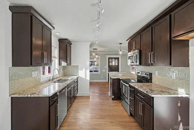 a kitchen with stainless steel appliances granite countertop a sink stove and cabinets
