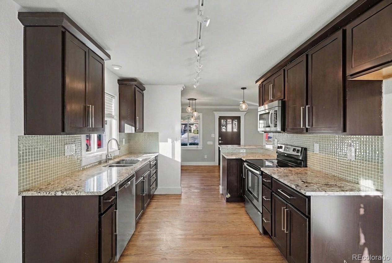 2580 South Perry Street Denver, CO 80219 - Photo 6 of 28 a kitchen with stainless steel appliances granite countertop a sink stove and cabinets