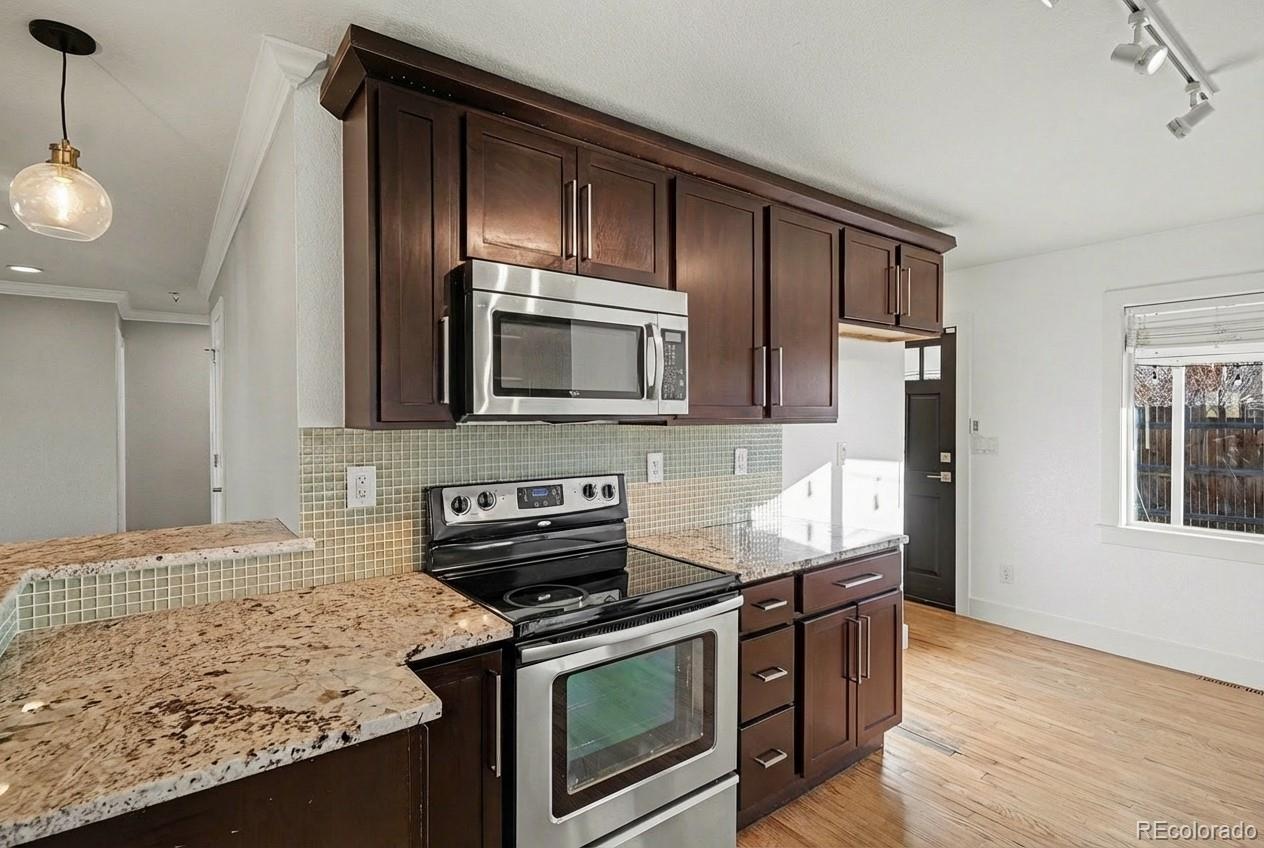2580 South Perry Street Denver, CO 80219 - Photo 9 of 28 a kitchen with granite countertop wooden cabinets and stainless steel appliances