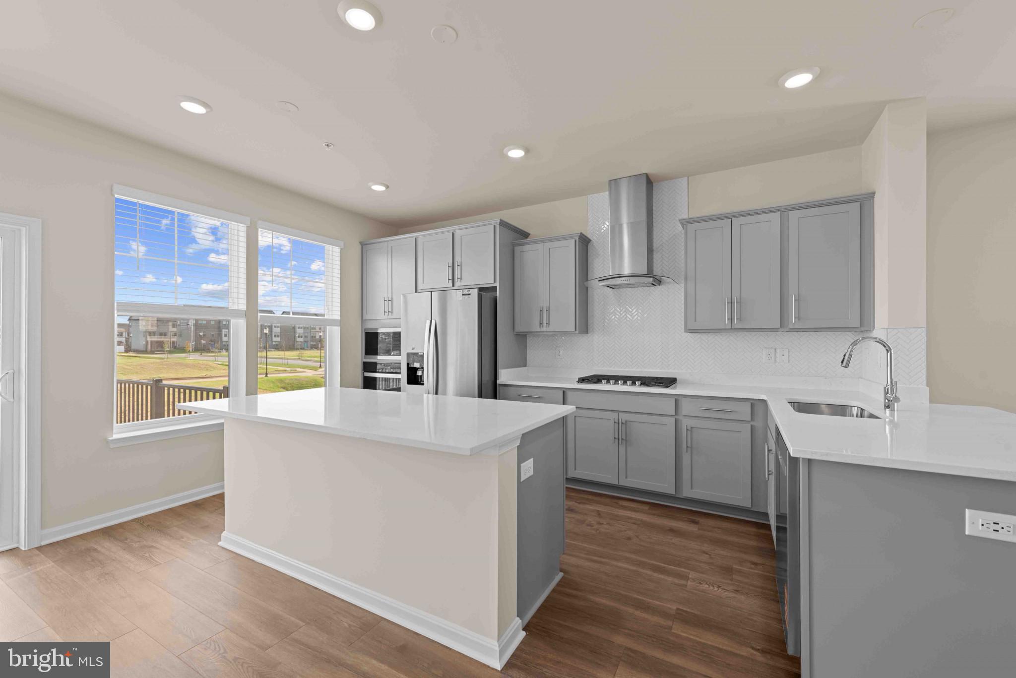 377 Ensemble Way Frederick, MD 21701 - Photo 12 of 45 a large kitchen with stainless steel appliances granite countertop a sink a stove a refrigerator and island with wooden floor