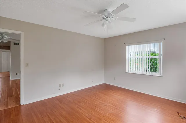 a view of a room with wooden floor and a ceiling fan