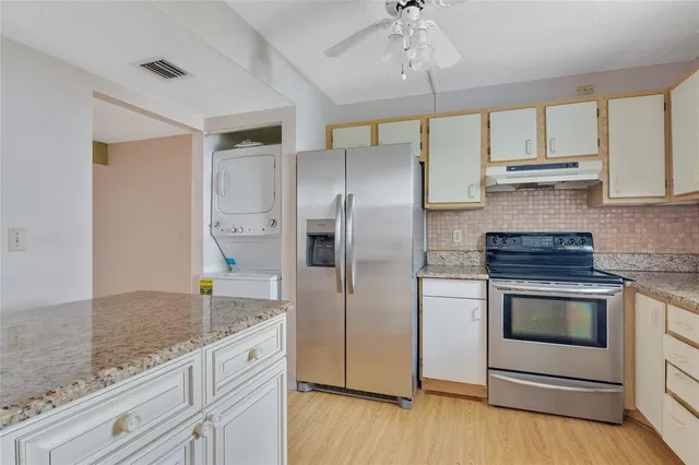 a kitchen with stainless steel appliances granite countertop a sink a stove a refrigerator and island with wooden floor