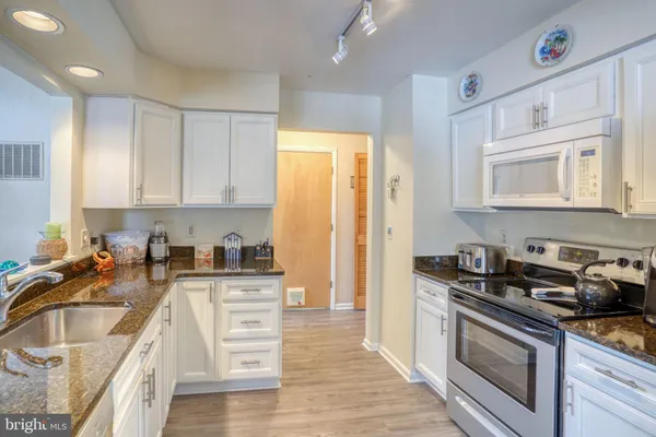 a kitchen with granite countertop a sink a stove and cabinets