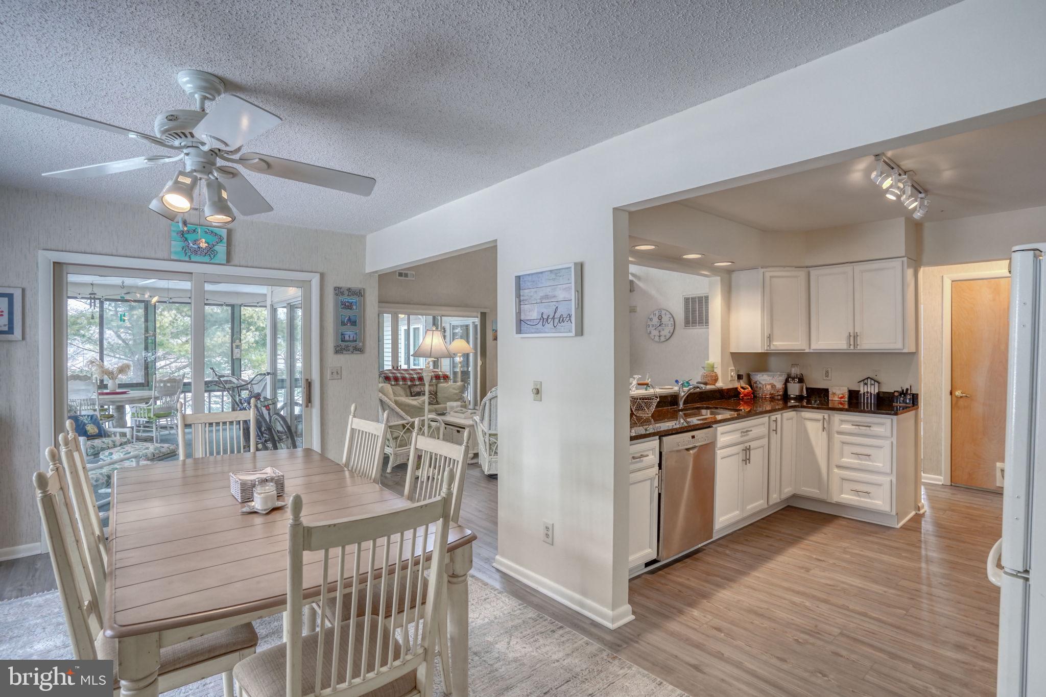 18488 Belle Grove Road, Unit 3 Lewes, DE 19958 - Photo 20 of 48 a kitchen with stainless steel appliances granite countertop a stove top oven a refrigerator a dining table and chairs with wooden floor