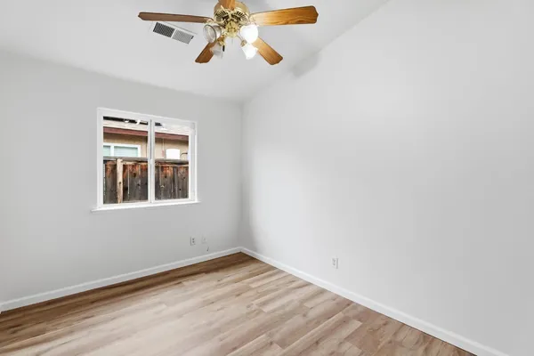 an empty room with wooden floor closet and windows