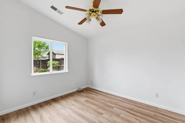 an empty room with a window and a fan