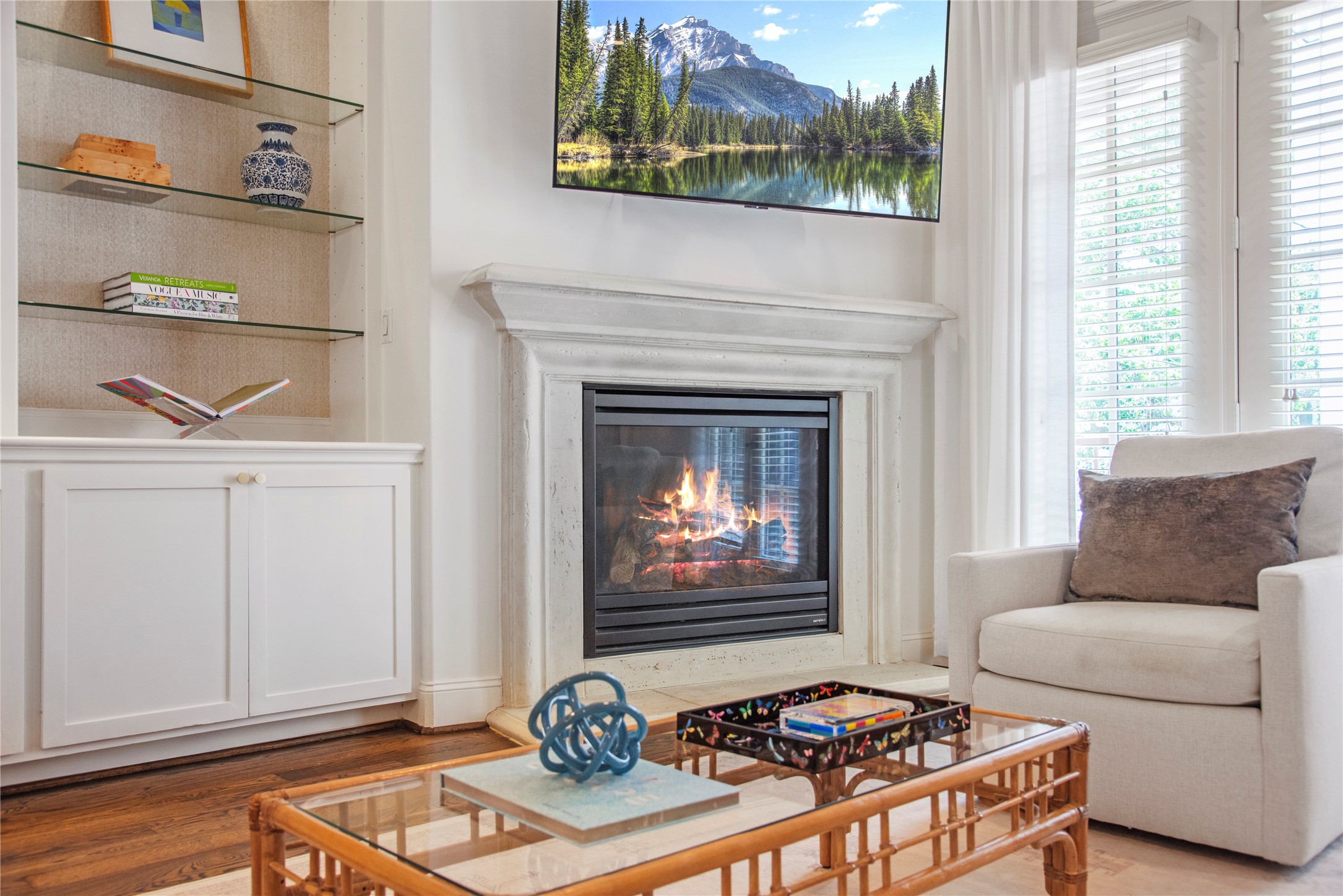 1537 Haddon Street Houston, TX 77006 - Photo 9 of 48 Cozy living area with a modern gas fireplace and elegant mantel. Features built-in shelving, a large window with blinds and French door to the second floor balcony, and a comfortable armchair. Perfect for relaxing or entertaining.