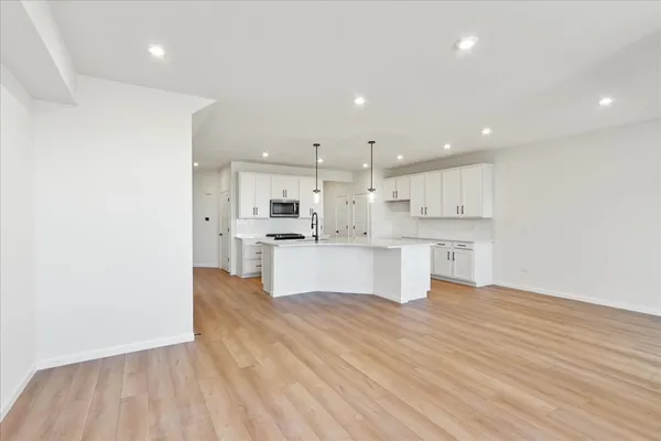 a large kitchen with kitchen island a sink dishwasher a stove and white cabinets with wooden floor