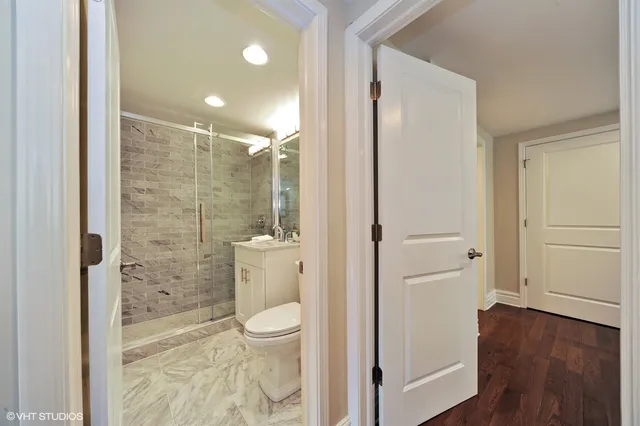 a bathroom with a granite countertop toilet a sink and a glass door