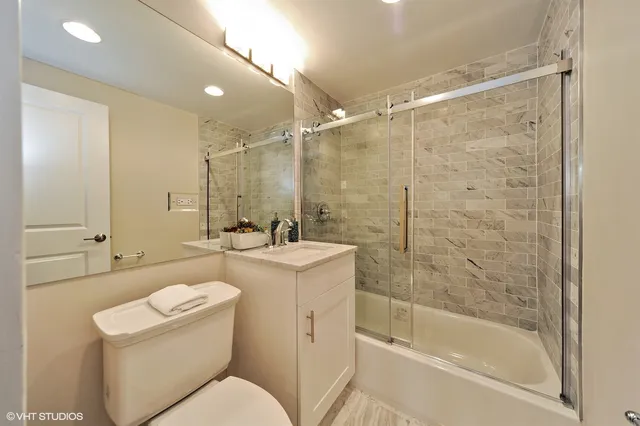a bathroom with a bathtub shower sink mirror and toilet