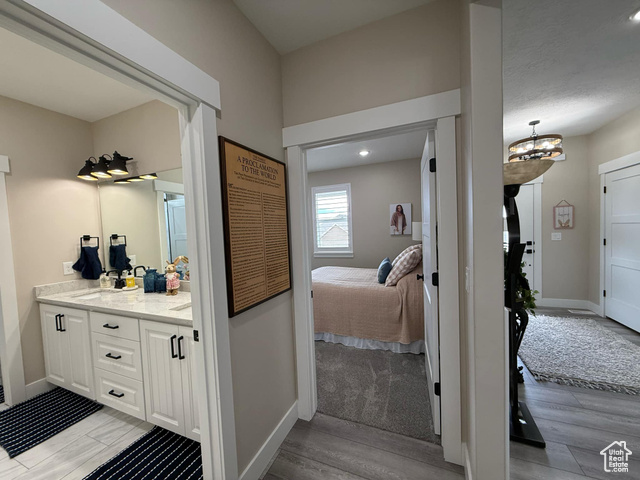 1240 West 2360 North Helper, UT 84526 - Photo 57 of 79 Bathroom with baseboards, connected bathroom, wood finished floors, vanity, and an inviting chandelier