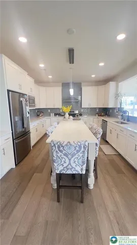 a dining room with stainless steel appliances granite countertop furniture wooden floor and a kitchen view