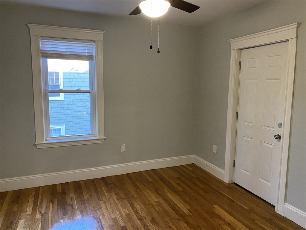 281 Belgrade Avenue, Unit 3 Boston, MA 02131 - Photo 12 of 14 a view of an empty room with wooden floor and a window