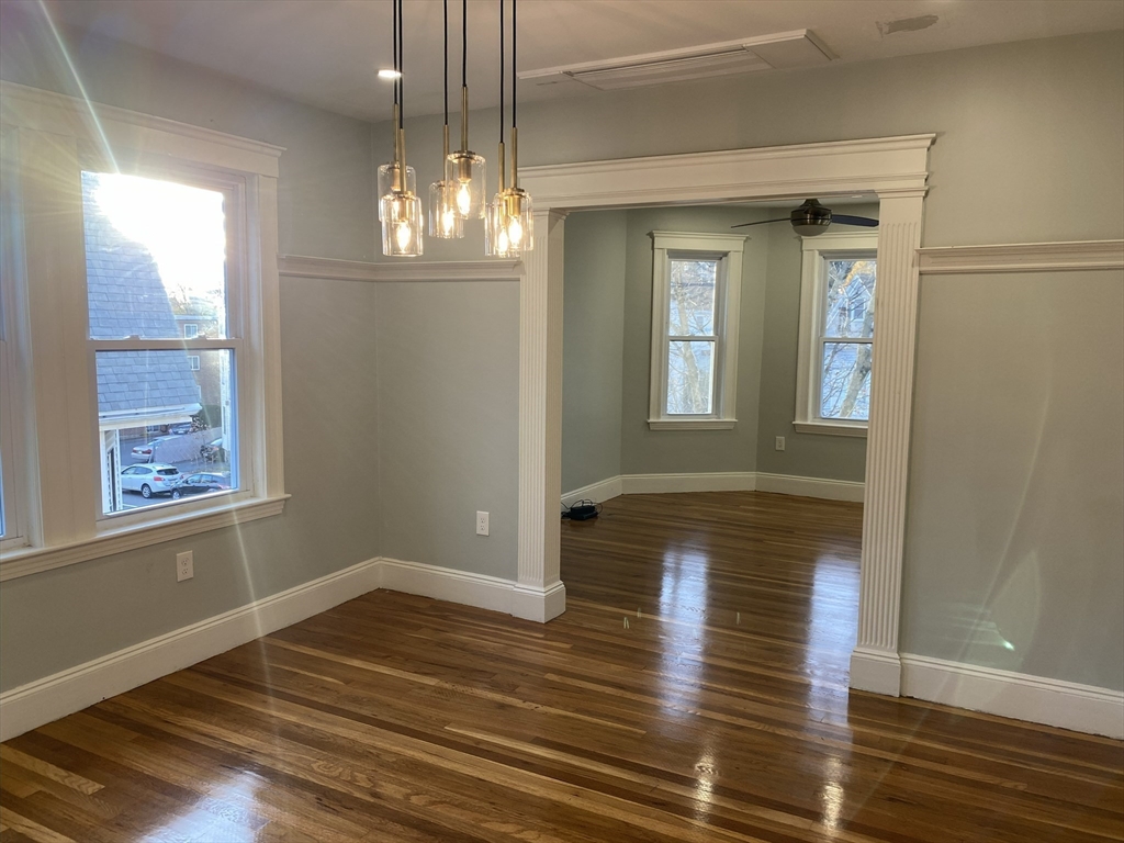 281 Belgrade Avenue, Unit 3 Boston, MA 02131 - Photo 8 of 14 a view of an empty room with wooden floor and a window