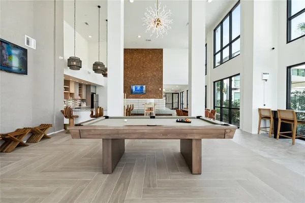 a dining hall with couches and potted plants with wooden floor