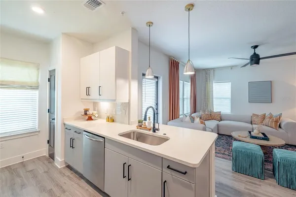 a kitchen with a sink dishwasher a stove a refrigerator and white cabinets with wooden floor