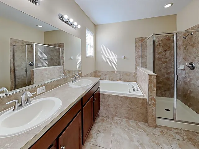 a bathroom with a granite countertop double vanity sink mirror and shower