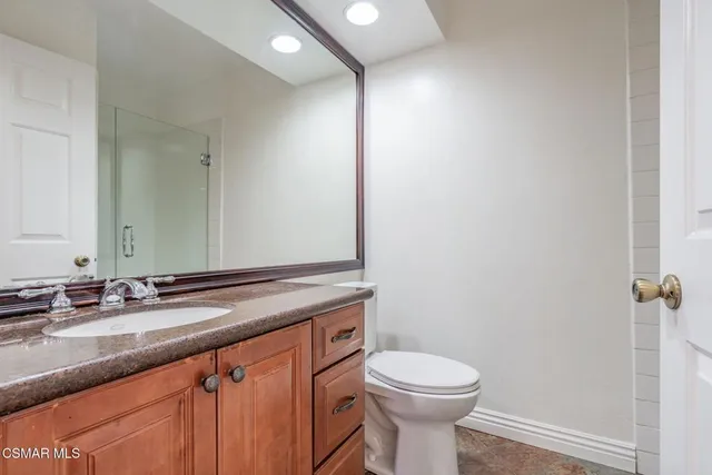 a bathroom with a granite countertop sink a toilet and a mirror