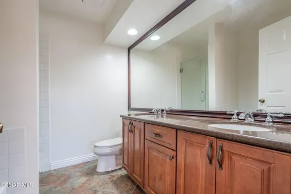 a bathroom with a granite countertop sink a toilet and a mirror