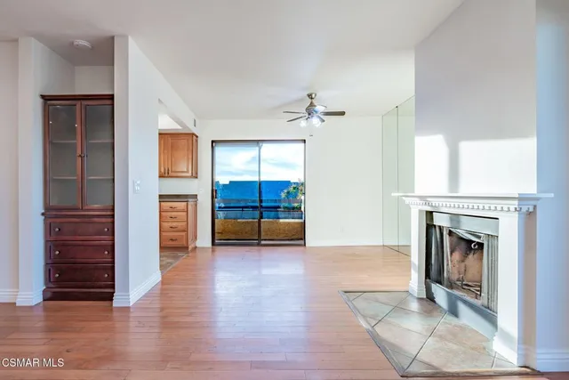 an empty room with wooden floor fireplace and windows