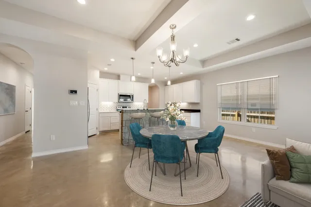 a dining room with kitchen island stainless steel appliances furniture a chandelier and kitchen view