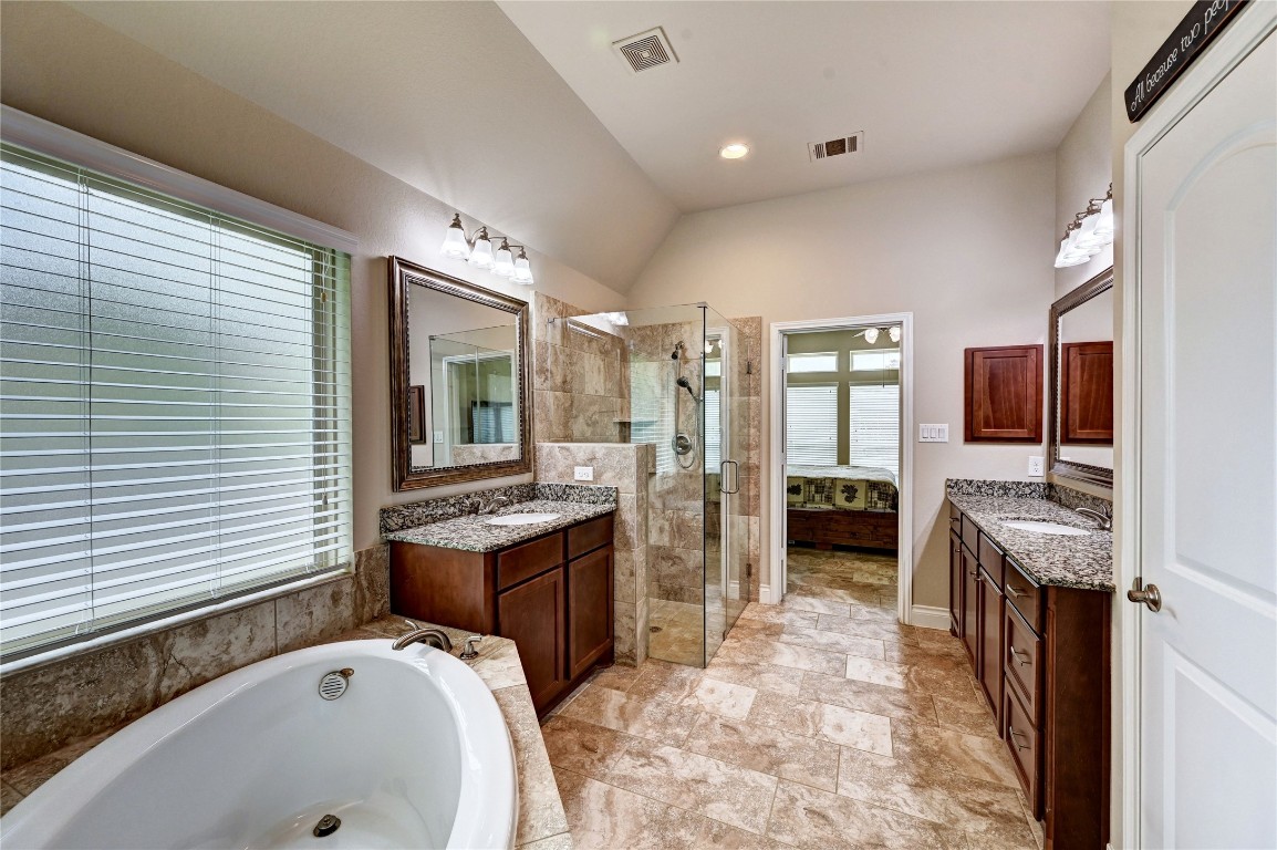 335 Fox Trail Road Montgomery, TX 77316 - Photo 19 of 47 This spacious primary bathroom features a luxurious soaking tub, a glass-enclosed shower, double vanities with granite countertops, and ample natural light from a large window.