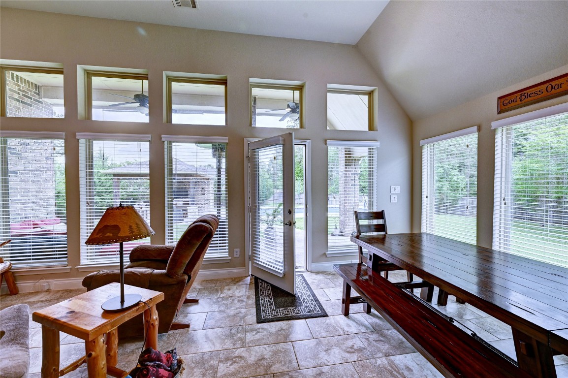 335 Fox Trail Road Montgomery, TX 77316 - Photo 23 of 47 This bright and inviting room features large windows with blinds, offering plenty of natural light and a view of the backyard. The space includes a cozy sitting area alongside a wooden dining table with benches, creating a warm, welcoming atmosphere perfect for relaxation and dining.