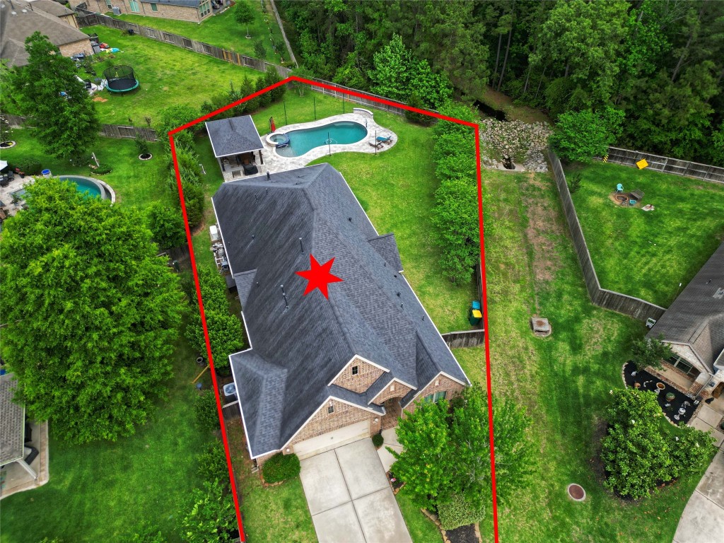 335 Fox Trail Road Montgomery, TX 77316 - Photo 3 of 47 This aerial photo showcases a spacious property with a large backyard, featuring a swimming pool and surrounding greenery. The house has a modern roof design and is located in a well-kept neighborhood, offering both privacy and outdoor leisure space.