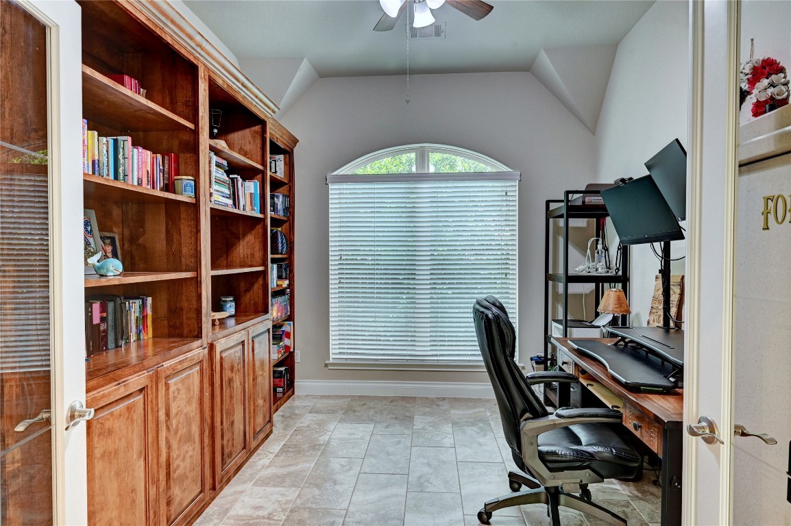 335 Fox Trail Road Montgomery, TX 77316 - Photo 37 of 47 This photo showcases a home office with a large window featuring blinds, filling the room with natural light. It includes built-in wooden bookshelves on creating a cozy and functional workspace.