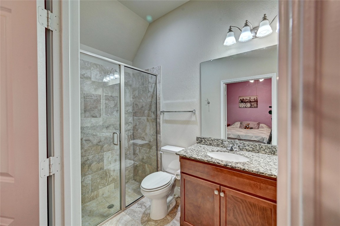 335 Fox Trail Road Montgomery, TX 77316 - Photo 40 of 47 This secondary bathroom features a modern design with a tiled walk-in shower, granite countertop, and wooden cabinetry. The room is well-lit with three overhead lights, and there's a view into an adjacent bedroom.