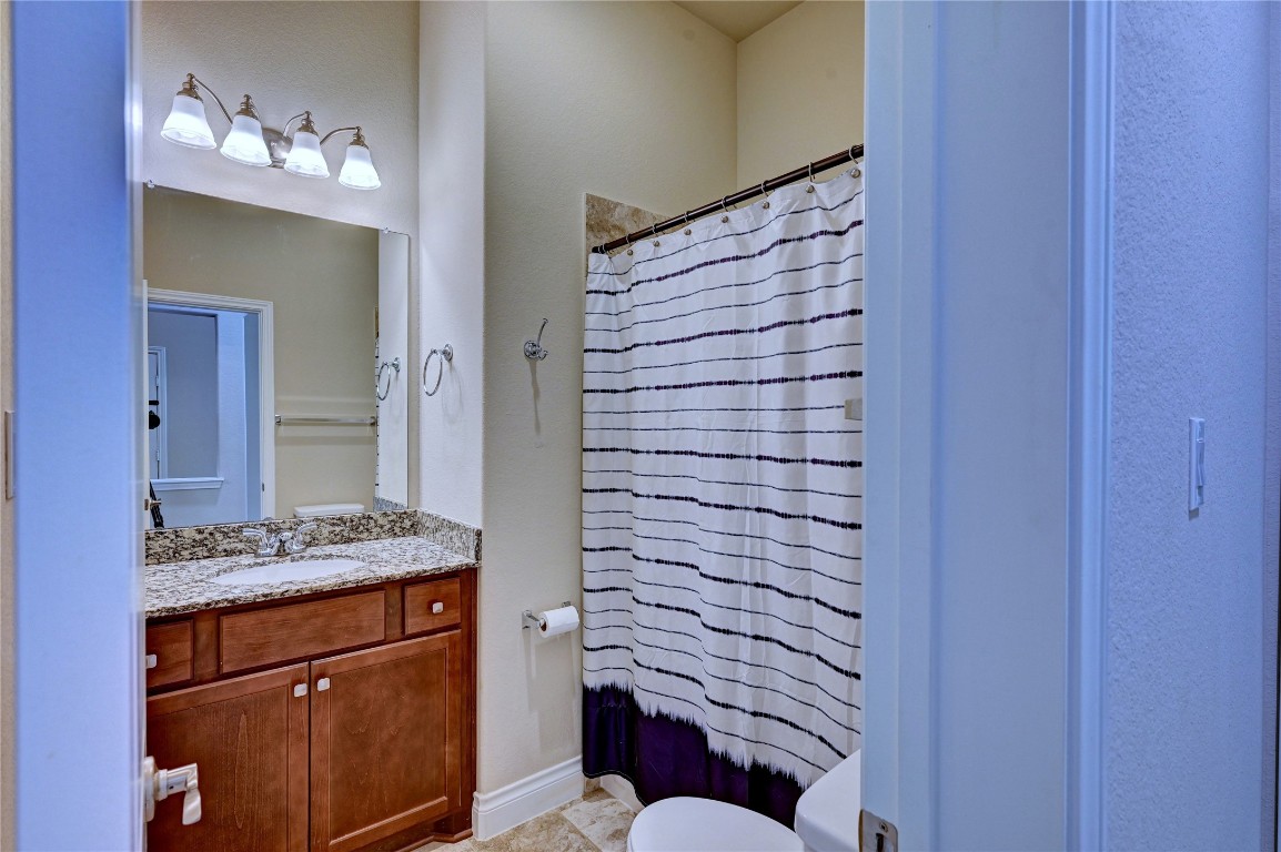 335 Fox Trail Road Montgomery, TX 77316 - Photo 43 of 47 This secondary bathroom features a granite countertop with a sink, wooden cabinetry, and a mirror with overhead lighting. It includes a bathtub/shower combo, and the walls are painted in a neutral tone.