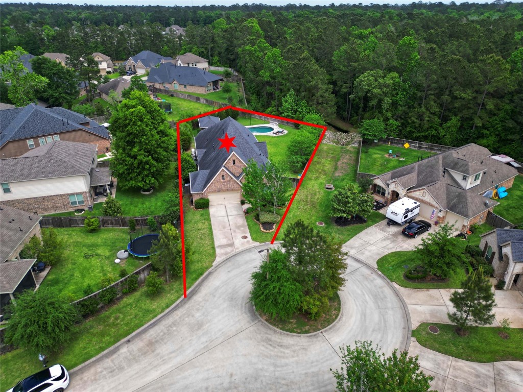 335 Fox Trail Road Montgomery, TX 77316 - Photo 46 of 47 This aerial photo showcases a spacious home on a cul-de-sac, featuring a large 16,035 sqft.lot that extends back with a private pool, spa and cabana with an outdoor kitchen. The property is surrounded by mature trees, providing privacy and a serene setting in a well-maintained neighborhood.