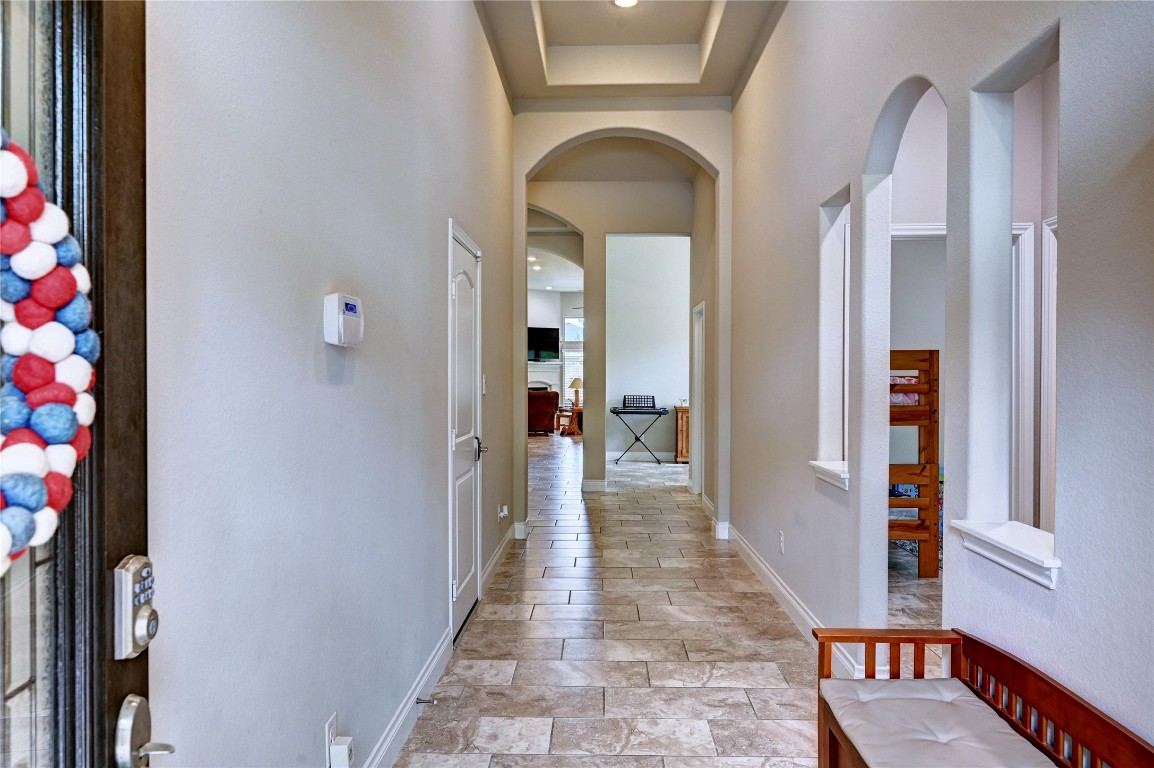335 Fox Trail Road Montgomery, TX 77316 - Photo 6 of 47 This photo showcases a bright, welcoming extended hallway with tiled floors and high ceilings. It features arched doorways and cutouts, adding architectural interest. The hallway leads to an open living area, creating a spacious feel.