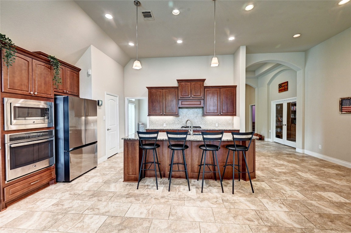 335 Fox Trail Road Montgomery, TX 77316 - Photo 10 of 47 This spacious kitchen features modern stainless steel appliances, a large island with seating for four, and elegant tile flooring. High ceilings and recessed lighting enhance the open, airy feel, while rich wood cabinetry provides ample storage.