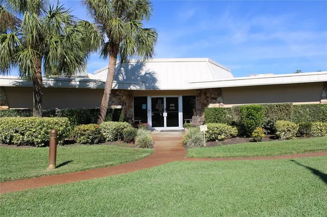 a view of a house with a big yard and palm trees