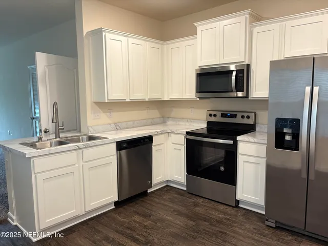 a kitchen with stainless steel appliances white cabinets a sink and a microwave