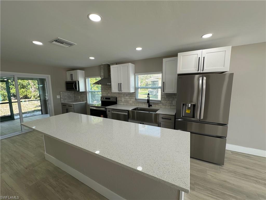 9165 Seville Road Fort Myers, FL 33967 - Photo 4 of 19 a large kitchen with stainless steel appliances a refrigerator a stove a sink dishwasher and a refrigerator with wooden floor