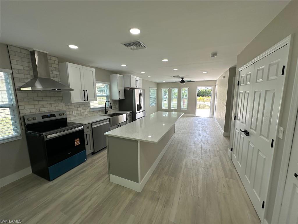 9165 Seville Road Fort Myers, FL 33967 - Photo 6 of 19 a kitchen with stainless steel appliances granite countertop a stove a sink dishwasher a refrigerator and white cabinets with wooden floor