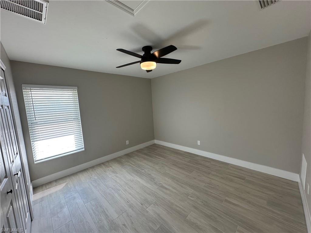 9165 Seville Road Fort Myers, FL 33967 - Photo 9 of 19 an empty room with wooden floor ceiling fan and windows