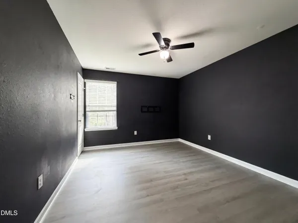 an empty room with windows and fan