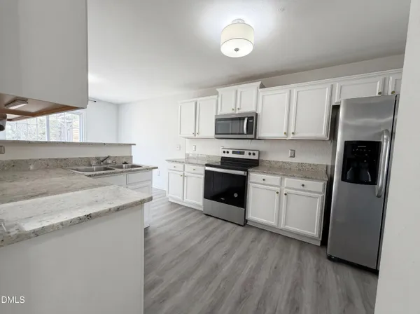 a kitchen with kitchen island granite countertop a sink cabinets and stainless steel appliances
