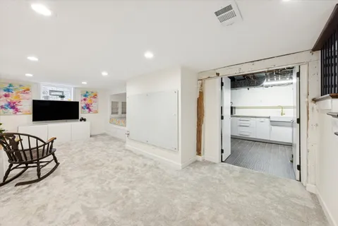 a view of a livingroom with a flat screen tv wooden floor and a refrigerator