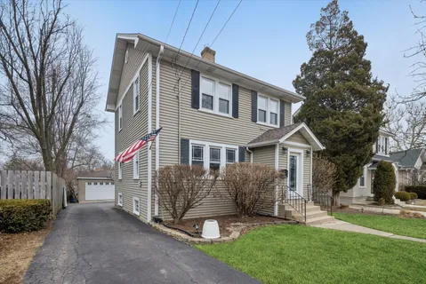a front view of a house with a garden and trees