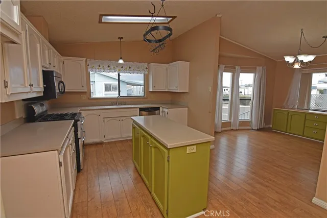 a kitchen that has a sink a microwave oven a stove and white cabinets with wooden floor