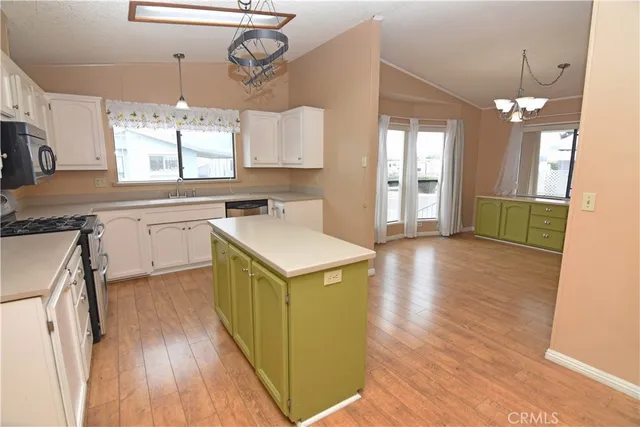 a kitchen with a sink a counter space wooden floor and stainless steel appliances