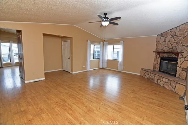 a view of an empty room with wooden floor and a fireplace