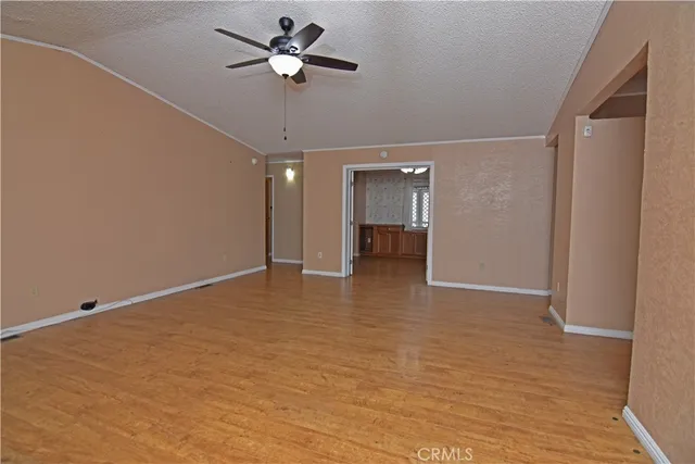 a view of empty room with wooden floor and ceiling fan
