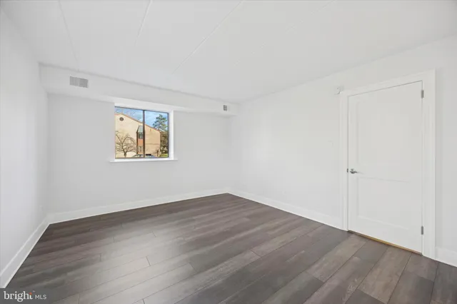 an empty room with wooden floor and window