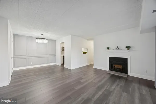 a view of an empty room with wooden floor fireplace and a window